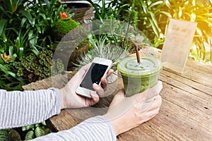 Hand hold smartphone or mobile phone and green tea