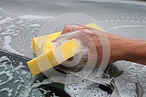 Hand hold sponge over the car for washing.