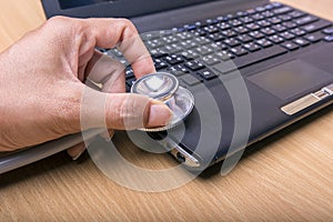 Hand hold stethoscope over computer computer maintenance concept