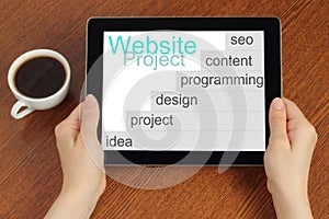 Hand hold tablet pc with website project's development steps