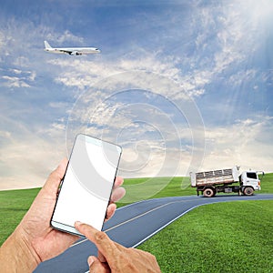 hand hold and touch screen smart phone with airplane in the sky, dumper truck on road blue sky background,open high season travel