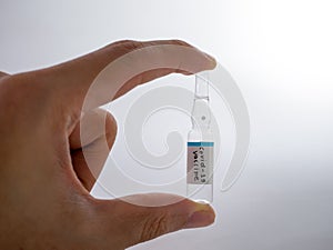 Hand hold transparency medical injection label text & x22;COVID-19 vaccine& x22;  on white background
