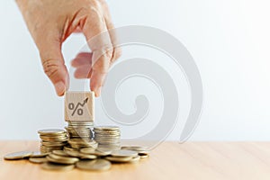 hand hold wood cube block with increasing percent icon on stack of coins. Money, Financial, Business Growth concept, including