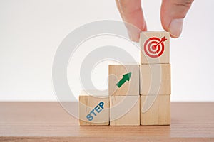 Hand hold wooden cube with the word start and arrows pointing up to  target icon. for business success, growth,