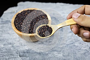 Hand hold a wooden spoon, riceberry on wooden spoon