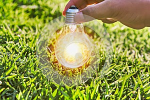 hand holdging light bulb on grass with solar energy. power eco c