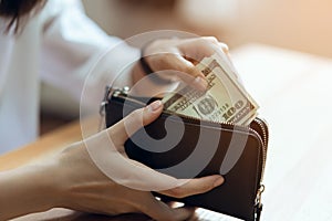 Hand holding 100 dollars bills in wallet. The concept of spending by cash.