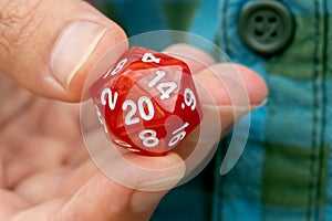 Hand holding a 20-sided d20 dice for RPG gaming, fingers closeup detail, one person, role-playing games, larp live action roleplay