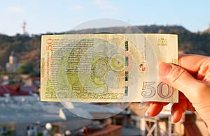 Hand Holding 50 Georgian Lari Banknotes in Reverse Side with Tbilisi City View in Backdrop