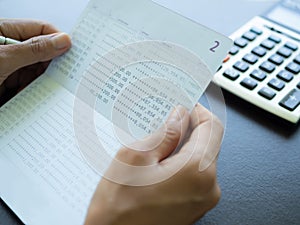 Hand holding account book bank with calculator on woonden background..