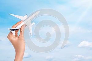 Hand holding airplane over blue sky background. Flight, travel concept