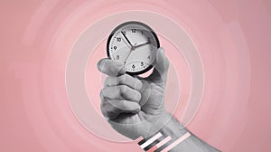 Hand Holding Alarm Clock Against Plain Background