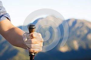 Hand holding alpenstock and mountain background photo