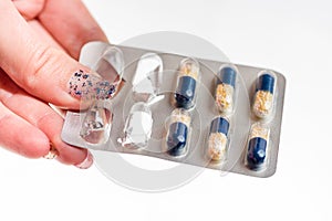 Hand holding antibiotics capsules or painkillers isolated on white. Medicine concept, pills close up, copy space