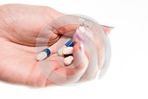 Hand holding antibiotics capsules or painkillers isolated on white. Medicine concept, pills close up, copy space