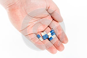 Hand holding antibiotics capsules or painkillers isolated on white. Medicine concept, pills close up, copy space