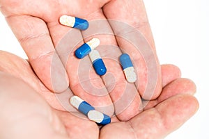 Hand holding antibiotics capsules or painkillers isolated on white. Medicine concept, pills close up, copy space