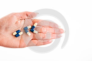 Hand holding antibiotics capsules or painkillers isolated on white. Medicine concept, pills close up, copy space