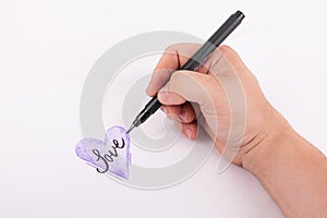 Hand holding a artist black ink pen hand sketched Purple Heart on white background