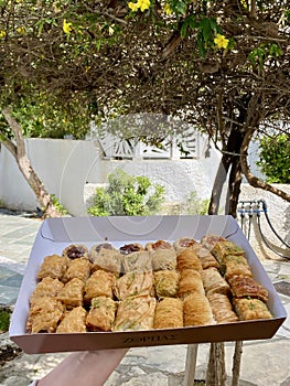 Hand holding Baklava sweets box outside, Turkish traditional pastry, Pistachio dessert