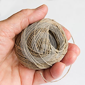 Hand holding a ball of natural hemp twine, ready to wrap a consignment photo
