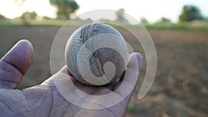 Hand holding ball. Old rustic Cricket ball holding in hand with grey color. Cork core round elastic ball closeup