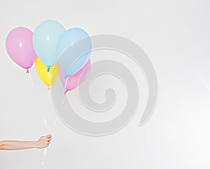 Hand holding balloons. Holiday concept. Colorful party balloons background. Isolated on white. Copy space