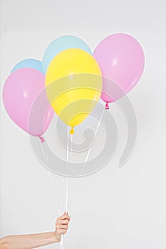 Hand holding balloons. Holiday concept. Colorful party balloons background. Isolated on white. Copy space