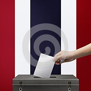 Hand holding ballot paper for election vote at thailand national flag on background. Thailand voting concept