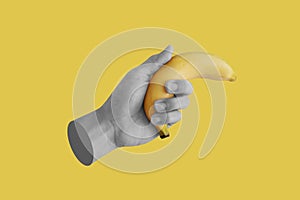 Hand holding banana, isolated on yellow background