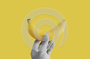 Hand holding banana, isolated on yellow background