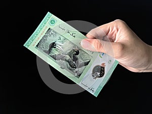 Hand holding a Bank Negara Malaysia 5 Ringgit Money over black background