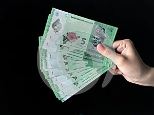 Hand holding a Bank Negara Malaysia 5 Ringgit Moneys over black background