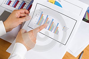 Hand holding bar chart graph while looking at financial data