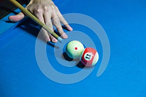 Hand holding billiard stick cue on a pool table ready to shot ball