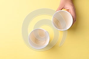 Hand holding biodegrable coffee cup on yellow background