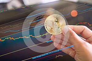 Hand holding Bitcoin crypto currency with blur graph candlestick chart trade forex growth data stock market digital signal Trend