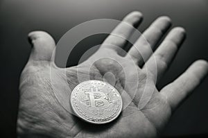 Hand holding bitcoin. Tonned vintage style photo.