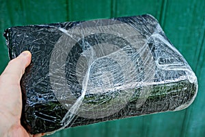 Hand is holding a black box in gray cellophane