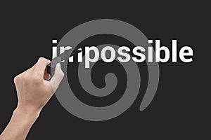 Hand holding black eraser changing the word impossible
