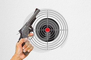 Hand holding black gun with shooting target background