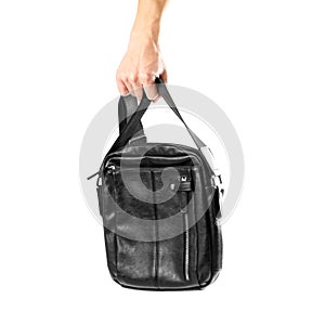 Hand holding black leather men`s bag. Close up. Isolated on white background