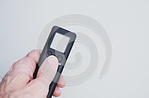 Hand holding a black remote controller on gray background for a copy space