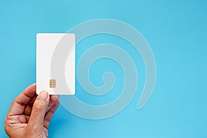 Hand holding blank credit chip card on blue background