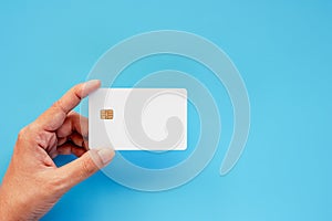Hand holding blank credit chip card on blue background