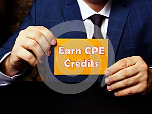 Hand holding a blank piece of paper with inscription Earn CPE Credits . Close up white business card