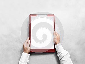 Hand holding blank red clipboard with white paper design mockup