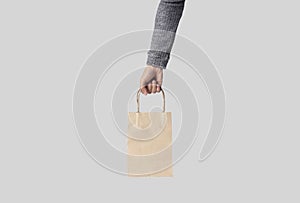 Hand holding blank white paper bag for mockup template advertising and branding isolated on white background