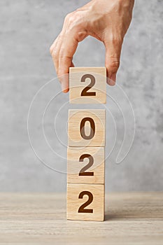 Hand holding block 2022 text on table. Resolution, strategy, plan, goal, motivation, reboot, business and New Year holiday