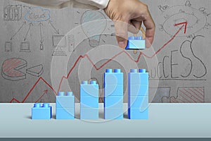 Hand holding blue block complete growth bar graph shape